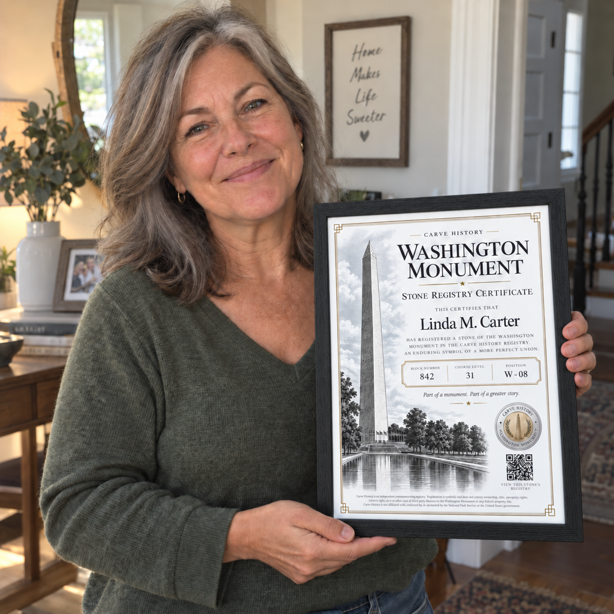 Linda holding her framed Washington Monument Stone Registry Certificate at home